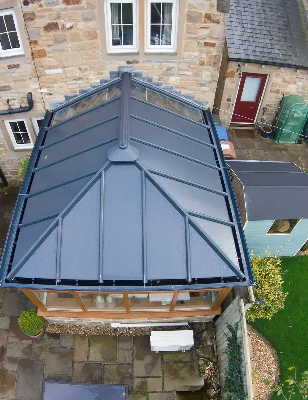 Aerial view of a dark grey tiled conservatory roof replacement on a house.